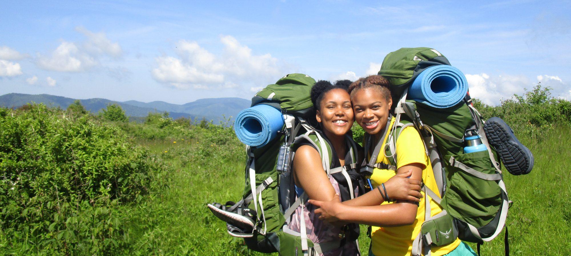 Two young women with backpacks smiling